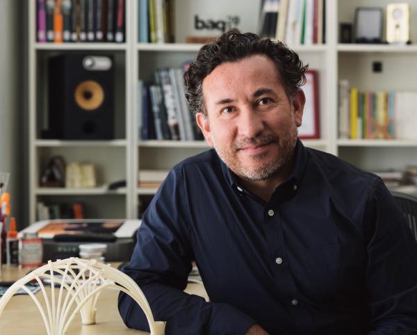 Benjamin Ibarra Sevilla sitting in his office in front of a bookshelf with a 3D-printed object on the desk in front of him