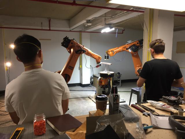 Two students look at the KUKA robotic arms in action
